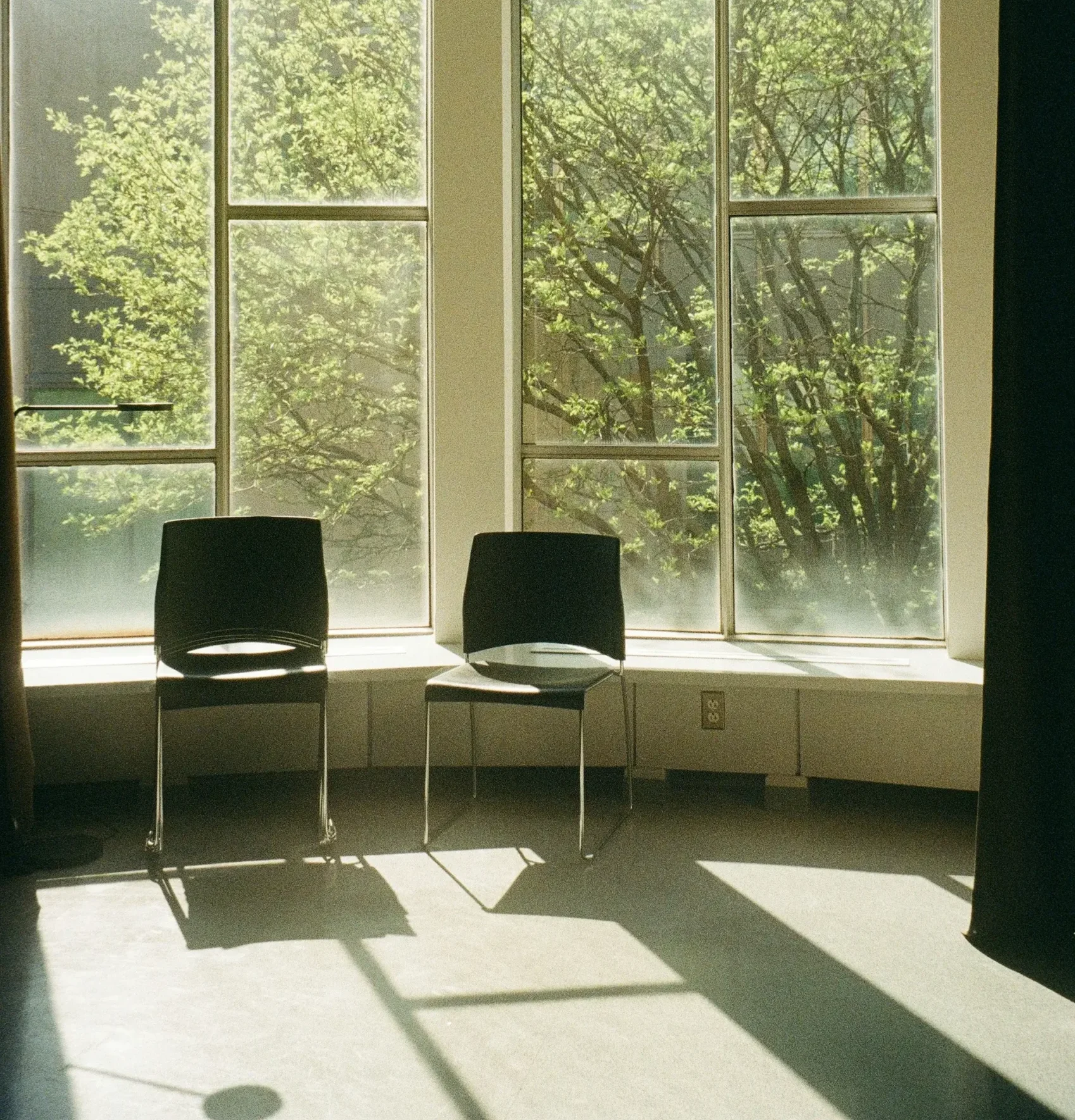 A pair of chairs placed before a window, creating a cozy seating area filled with sunlight.